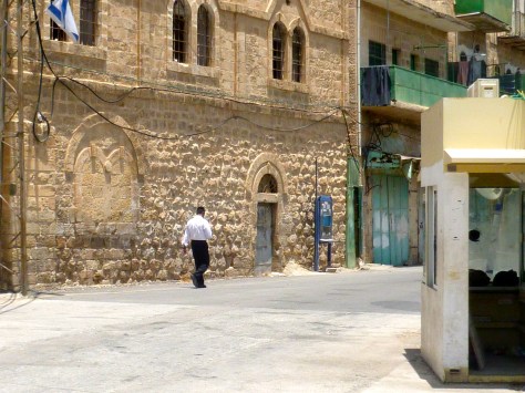 An Israeli settler walking past the military post on Shuhada Street, Hebron.